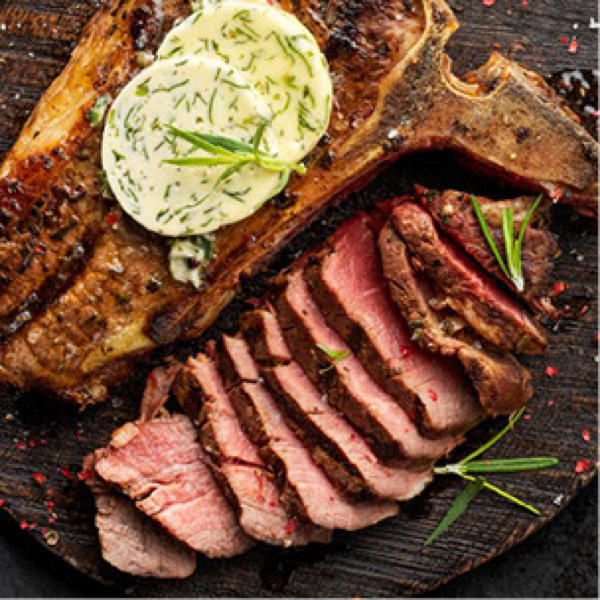 Gegrilltes Steak mit Kr&auml;uterbutter und in Scheiben geschnittenem Fleisch auf einem Holzbrett, garniert mit Rosmarin.